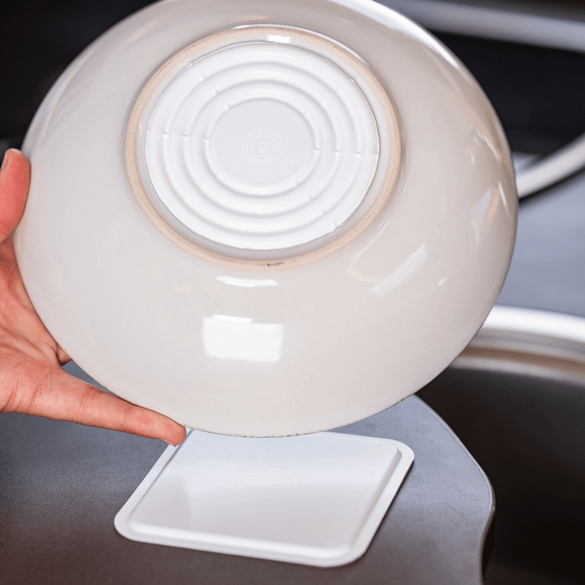 Tellerunterseite mit angebrachtem MagUp Pad und darunter liegendem Nano-Gel Pad auf dem Tisch – rutschfeste DIY Magnetlösung für sicheren Halt von Geschirr im Haushalt, Camping oder Wohnwagen